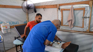 An MSF staff checks the injury of Saad Hussein, who is forced to live with an external fixator after he was injured in 2025 during a food distribution by the Gaza Humanitarian Foundation. Al Mawasi primary healthcare center, Khan Younis, Gaza.