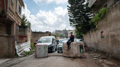 Hussam Odeh sits on a roadblock placed by Israeli soldiers in his neighborhood outside his home in Huwwara on 13 April 2023