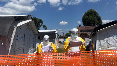 MSF medical teams debrief from the red zone after patient rounds, communicating with medical staff in the green zone. Patient files are considered contaminated and remain in the red zone, with information relayed verbally to ensure infection prevention measures are maintained at the Ebola Treatment Centre in Lwiro, South Kivu.