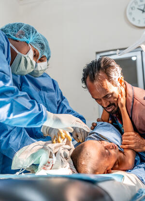 Kutupalong Refugee Camp, Rohingya Response: Shofi Mohammad (4 years) is getting treatment for multiple abscesses in axilla and back in the ER of the MSF Kutupalong hospital. While Dr. Hasna Hena Mou and Medical Assistant Rajib Mazumdar are doing an incision and drainage, his father Anas Mohammad (50 years) tries to comfort him. The mother of Shofi and his brother are waiting outside. The family went to another health facility first, but they couldn't perform the procedure, that's why Shofi was referred to t