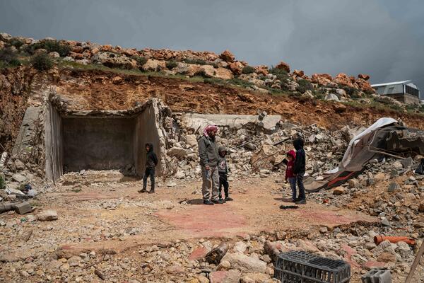 Mustafa Mlikat stands with his children next to the rubble of his house which was demolished by Israeli forces, in Douma on 13 April 2023.
