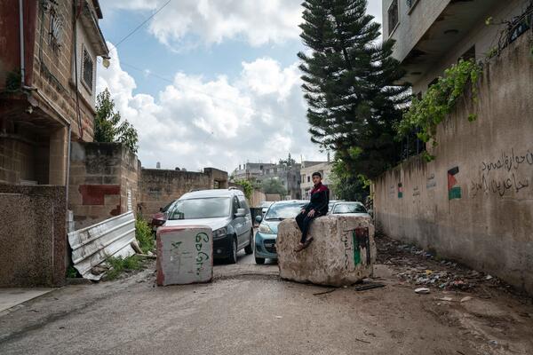 Hussam Odeh sits on a roadblock placed by Israeli soldiers in his neighborhood outside his home in Huwwara on 13 April 2023