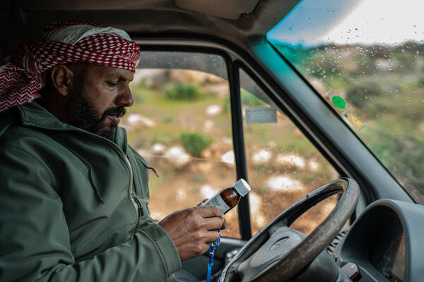 Mustafa Mlikat inspects a medicine bottle handed to him by his son in request to purchase a similar one for him, in Douma on 13 April 2023.