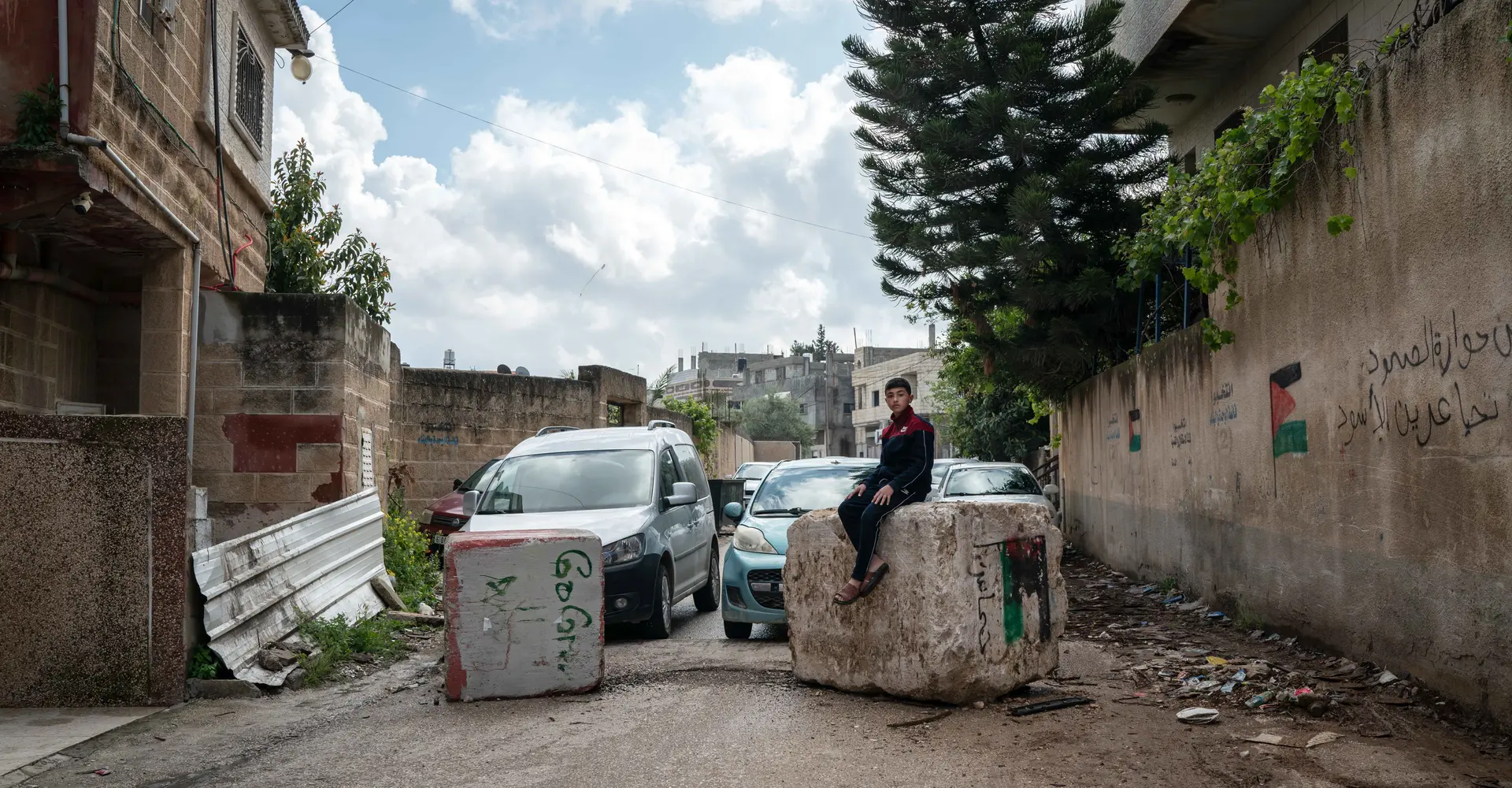 Hussam Odeh sits on a roadblock placed by Israeli soldiers in his neighborhood outside his home in Huwwara on 13 April 2023