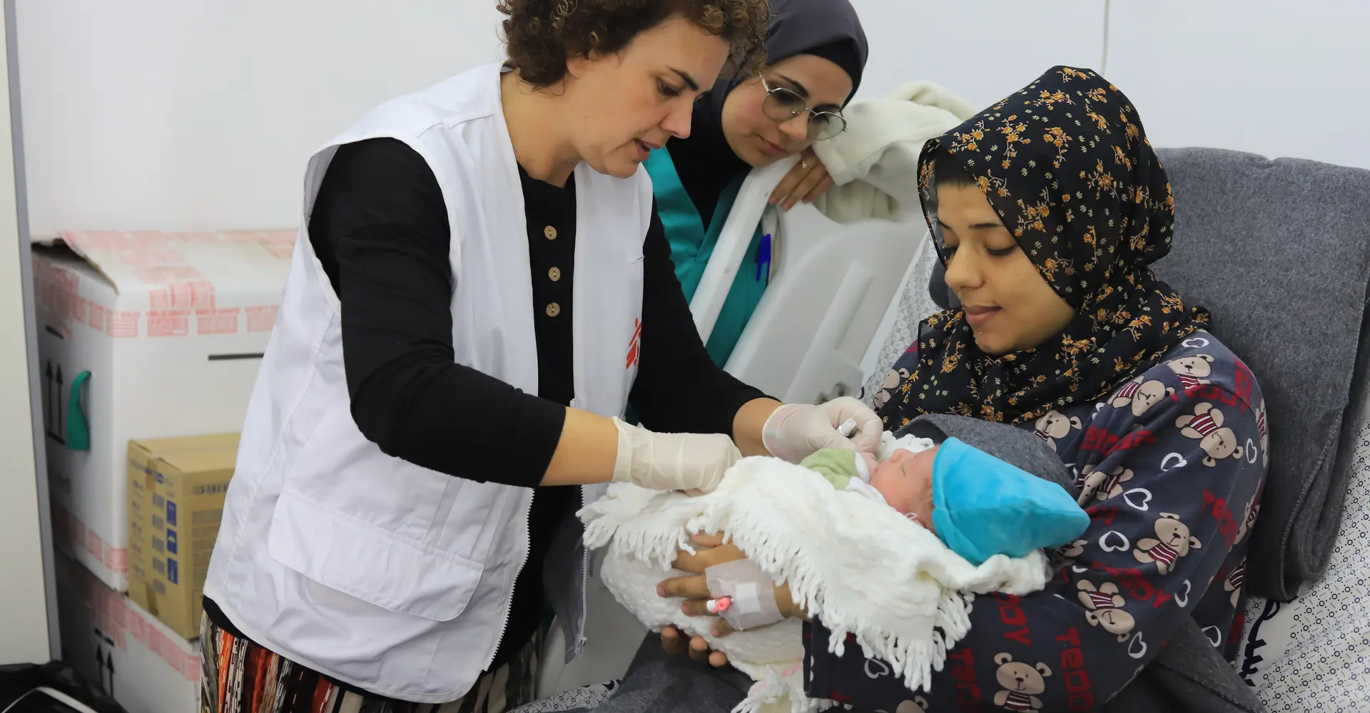 MSF medical staff discussing with patient and checking on newborn child in the Emirati hospital, Rafah, southern Gaza.