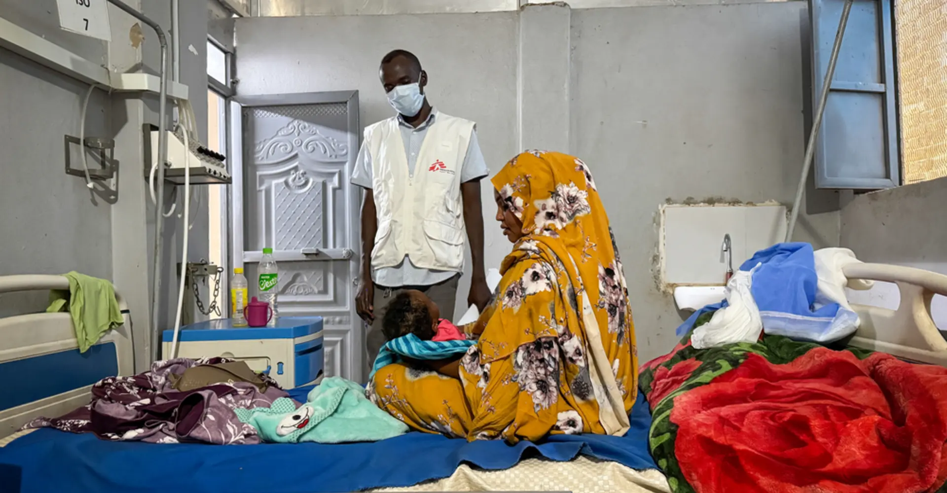 Ferdos holds her 11-month-old baby, Banan, who is infected with measles, in the isolation ward at El Geneina Teaching Hospital, supported by MSF. War forced Ferdos and her family to flee to El Geneina, where they live in overcrowded conditions with other families. Her son contracted measles and infected his 11-month-old daughter.