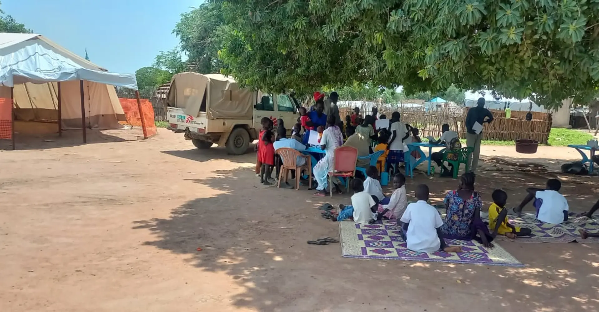 Families wait under the shade of a tree at a seasonal malaria prevention campaign site in Twic County. Through community-based services, MSF and local health authorities are expanding access to preventive care for children most at risk of malaria.