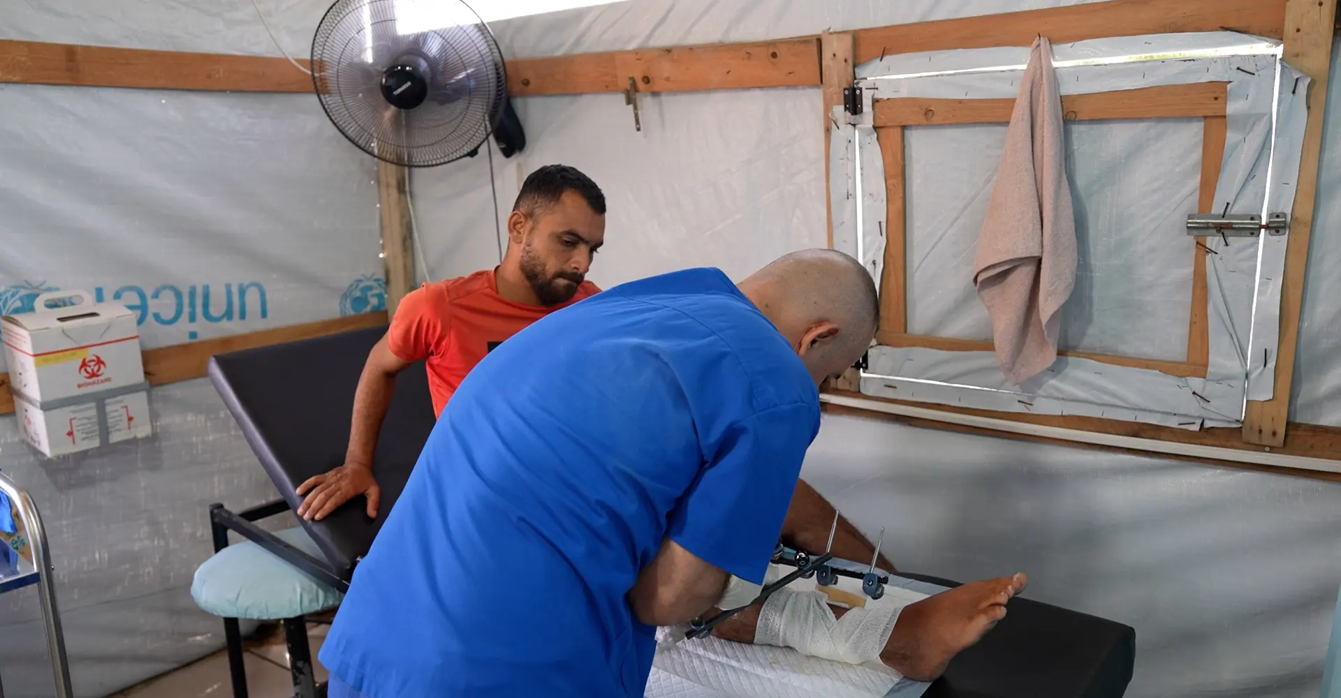 An MSF staff checks the injury of Saad Hussein, who is forced to live with an external fixator after he was injured in 2025 during a food distribution by the Gaza Humanitarian Foundation. Al Mawasi primary healthcare center, Khan Younis, Gaza.